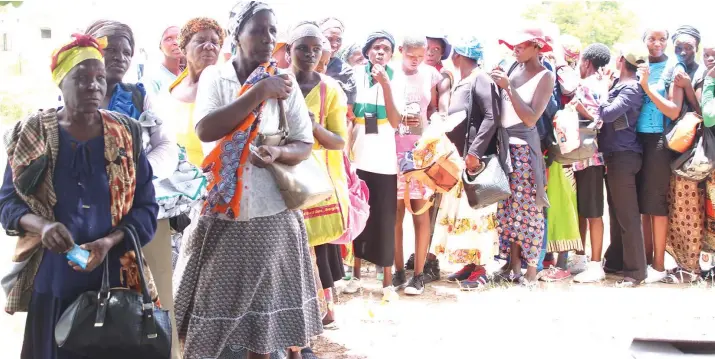  ??  ?? Berita Dube stands in front of the queue with other community members awaiting rations