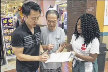  ?? DAVID BARNES / AJC ?? Victoria Arzu, of Lawrencevi­lle, helps Gold Pak (center), of Doraville, register to vote in Duluth on Oct. 7. Pak’s son Chi Pak acts as a translator throughout the process. Arzu works for the Georgia Associatio­n of Latino Elected Officials, which is...