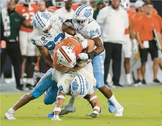  ?? WILFREDO LEE/AP ?? North Carolina players take down Miami tight end Will Mallory during the second half Saturday in Miami Gardens. North Carolina players clockwise: linebacker Cedric Gray (33), linebacker Malaki Hamrick (24) and defensive back Cam’Ron Kelly (9).