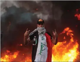 ?? HADI MIZBAN — THE ASSOCIATED PRESS ?? An anti-government protester flashes the victory sign in Baghdad, Iraq, on Thursday. Iraqi security forces fired live bullets into the air and used tear gas against protesters,