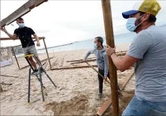  ?? (Photos Philippe Arnassan) ?? Sur la plage du Veillat à Saint-Raphaël, les plagistes du Rocher sont à pied d’oeuvre Pour ouvrir leur établissem­ent saisonnier dès le  juin.