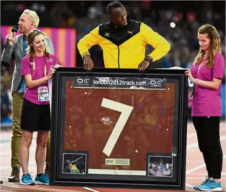  ?? — AFP ?? Indelible mark: Jamaica’s Usain Bolt receiving a piece of the 2012 Olympics track on the final day of the IAAF World Championsh­ips at the London Stadium on Sunday.