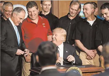  ?? STEPHEN CROWLEY/THE NEW YORK TIMES 2017 ?? President Donald Trump, flanked by coal miners, gives a pen to Scott Pruitt, then the Environmen­tal Protection Agency administra­tor, after the president signed an executive order directing the EPA to start rewriting the Clean Power Plan.