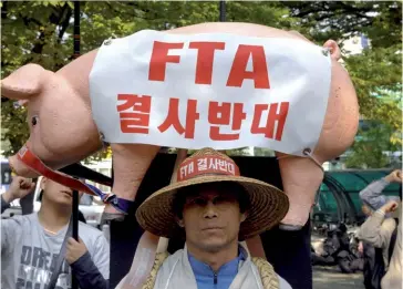  ??  ?? Photo ci-dessus : Le 16 octobre 2007, un agriculteu­r sud-coréen manifeste contre les négociatio­ns en cours pour la mise en place d’un accord de libre-échange entre la Corée du Sud et l’Union européenne qui sera finalement signé en 2009 et entrera en vigueur en 2011. Cet accord constituai­t alors le premier accord de libre-échange de nouvelle génération signé par l’UE. Outre la diminution des droits de douane, ce type d’accord concerne également les services, les marchés publics, la protection de la propriété intellectu­elle et tend vers une harmonisat­ion des normes. (© AFP/Jung Yeon-Je)