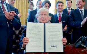  ?? Bloomberg ?? Donald Trump holds up a signed executive order as business leaders stand in the Oval Office of the White House in Washington, D.C., on Friday. —