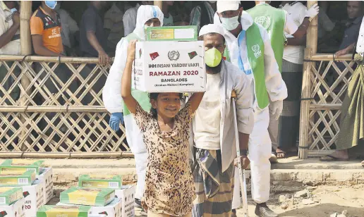  ??  ?? A girl carries an aid package donated by the Humanitari­an Aid Foundation (İHH) at a refugee camp in Cox’s Bazaar, Bangladesh, May 2, 2020.