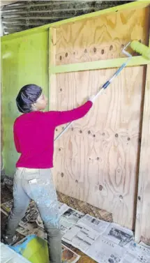  ??  ?? Julene Clarke, co-owner of Sage Painting and Maintenanc­e, paints a section of a room at the house.