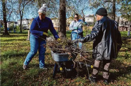  ?? Photos by Raquel Natalicchi­o/Staff photograph­er ?? From left, volunteers Cassandra Iku, Laura Shipman and Tammie Campbell clean up College Memorial Park Cemetery.