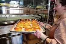  ?? Salgu Wissmath/The Chronicle ?? Poppy owner Reesa Kashuk takes a test batch of bagels out of the oven at her new bagel shop in Oakland.