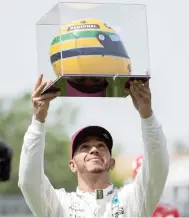  ??  ?? Mercedes driver Lewis Hamilton, of Great Britain, holds up a racing helmet of former F1 driver Ayrton Senna after winning pole position at the F1 Canadian Grand Prix auto race Saturday in Montreal. (AP)