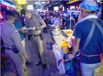  ??  ?? Police inspecting the passport of a foreigner in Bangkok’s Patpong district during the ‘X-Ray Outlaw Foreigner’ operation. — AFP photo