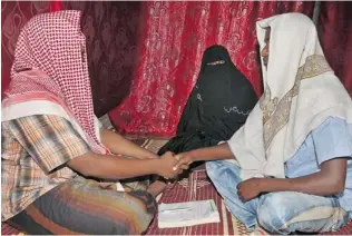  ?? PHOTOS: FARAH ABDI WARSAMEH/ THE ASSOCIATED PRESS FILES ?? Abdi Ali, 25, right, shakes hands with an Islamic cleric who marries eloping couples, left, as Ali’s girlfriend Anisa, 23, watches, during their marriage in Walaweyn, Somalia.