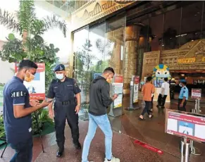  ??  ?? Tightened security: (Top) an auxiliary police officer checking people’s Mysejahter­a app before allowing them to enter sunway Pyramid mall in Bandar sunway. (right) shop owner ahmad Jomaa showing a Turkish carpet to customers at 1utama shopping Centre in Petaling Jaya. — saMuEL ONG and GLENN GuaN/The star