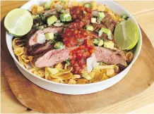  ?? MATTHEW MEAD/ THE ASSOCIATED PRESS ?? The most basic versions of Frito Pie heap hot chili and cheese on a mound of corn chips. Try it with a marinated flank steak instead and top with an assortment of fixings.