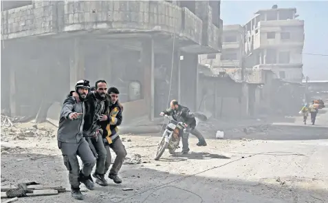  ??  ?? Civil defence volunteers help a man in Hammouriye­h during Syrian government shelling on rebel-held areas in the eastern Ghouta region