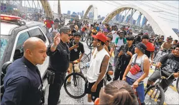  ?? Robert Gauthier Los Angeles Times ?? LAPD OFFICERS speak with BlocBoi Fame, a leader of the Goon Ride, after the group — numbering in the hundreds — gathered midspan on the 6th Street Viaduct, prompting police to shut the bridge down.