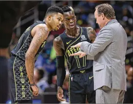  ?? CURTIS COMPTON / CCOMPTON@AJC.COM ?? Hawks Kent Bazemore and Dennis Schroder confer with coach Mike Budenholze­r during a victory over the Grizzlies in February.