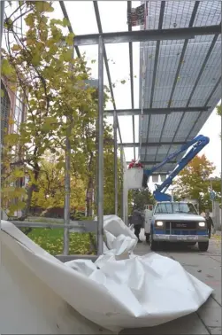  ?? RON SEYMOUR/The Daily Courier ?? Workers re-affix heavy canvas panels to the city-owned pergola along the Art Walk in downtown Kelowna on Wednesday morning. The panels, installed as part of security for the high-profile Jonathan Bacon murder trial in the nearby courthouse, blew down...