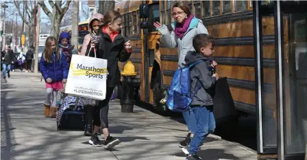  ?? ANGELA ROWLINGS PHOTOS / HERALD STAFF ?? HEADED FOR HOME: Students at the Mary E. Curley K-8 School in Jamaica Plain board a school bus after dismissal on Monday. Below, other students walk home.
