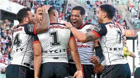  ?? GETTY IMAGES ?? The Warriors congratula­te skipper Roger Tuivasa-Sheck after his trysaving tackle on Tim Lafai of the Dragons on Saturday.