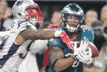  ??  ?? The Eagles’ Corey Clement catches a touchdown pass in front of the Patriots’ Marquis Flowers. The catch withstood an automatic scoring play review, even though it appeared Clement juggled the ball and failed to get both feet down in bounds. — THE...