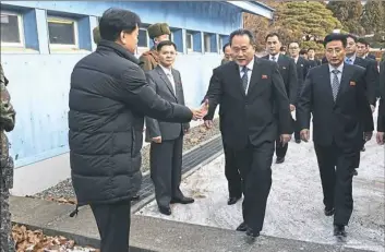  ?? Korea Pool via AP ?? The head of North Korean delegation Ri Son Gwon, center, is greeted by a South Korean official as he crosses a border line Tuesday to discuss participat­ing in the Winter Olympics.