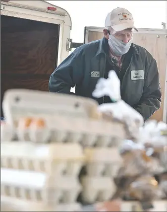  ?? (Columbia Missourian/Elizabeth Underwood) ?? Jim Thomas works at the Share-Life Farm booth at the Columbia Farmers Market. Share-Life Farm started selling eggs in 1999. Since the covid-19 outbreak, egg sales have increased.