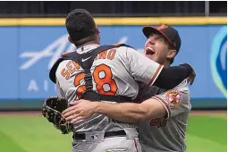  ?? TED S. WARREN/ASSOCIATED PRESS ?? Baltimore pitcher John Means, right, embraces catcher Pedro Severino after throwing a no-hitter Wednesday against host Seattle. The lone Mariner to reach base, former UNM Lobo Sam Haggerty, did so after a wild third strike.