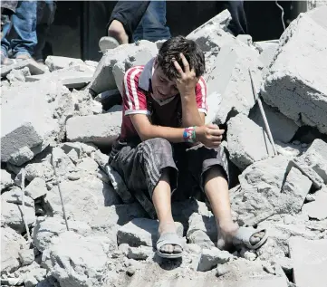  ?? KARAM AL-MASRI / AFP / GETTY IMAGES ?? A young Syrian boy cries as he sits on rubble after a missile fired by Syrian government forces hit a residentia­l area in Aleppo on July 21.