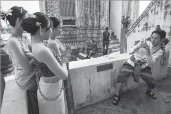  ?? BLOOMBERG VIA GETTY IMAGES ?? Chinese tourists in traditiona­l Thai dress pose for a photograph at Wat Arun in Bangkok, Thailand, on Wednesday.