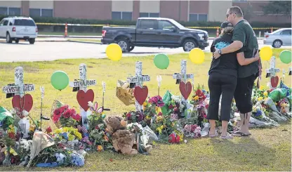  ?? COURTNEY SACCO/CALLER-TIMES-USA TODAY NETWORK ?? Mourners embrace at a makeshift memorial outside Santa Fe High School in Santa Fe, Texas, on May 22. The school has made a series of security changes since a shooting that killed 10.