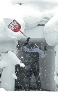  ?? HARALD SCHNEIDER / AFP ?? A man removes snow from his house on Tuesday in Ramsau am Dachstein, Austria, as heavy winter storms hit Europe.