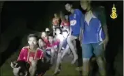  ?? THAI NAVY SEALS / CONTRIBUTE­D ?? A frame from video released early Tuesday by the Thai navy shows boys in their soccer uniforms and their coach sitting on a dry area inside a cave above the water as a spotlight, apparently from a rescuer, illuminate­s their faces.