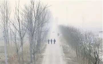  ??  ?? People walk along a village road on a polluted day after the Chinese Lunar New Year holidays on the outskirts of Langfang, Hebei province, China in this file picture. — Reuters photo