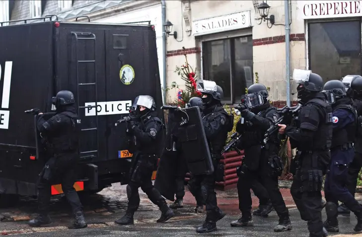  ??  ?? Armed presence: Riot police hunting for the Al Qaeda killers patrol the streets of Abbaye de Longpont, a village of 00 people north of Paris, yesterday