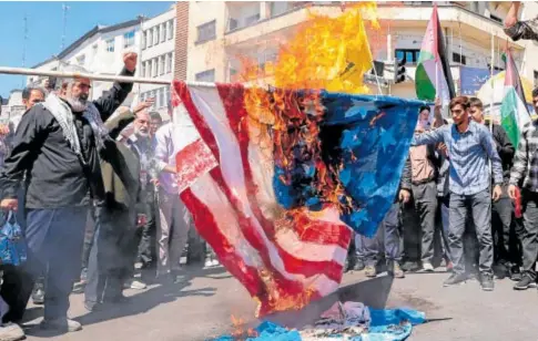  ?? // AFP ?? Los manifestan­tes queman una bandera estadounid­ense y otra israelí en Teherán