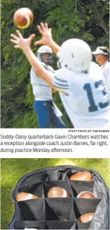  ?? STAFF PHOTO BY TIM BARBER STAFF PHOTO BY TIM BARBER ?? Soddy-Daisy quarterbac­k Gavin Chambers watches a reception alongside coach Justin Barnes, far right, during practice Monday afternoon. A bag of footballs awaits on the sideline at Soddy-Daisy practice.