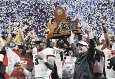  ?? John Bazemore The Associated Press ?? Georgia coach Kirby Smart and his team hold the Southeaste­rn Conference championsh­ip trophy after the sixth-ranked Bulldogs beat No. 4 Auburn 28-7 on Saturday in Atlanta.