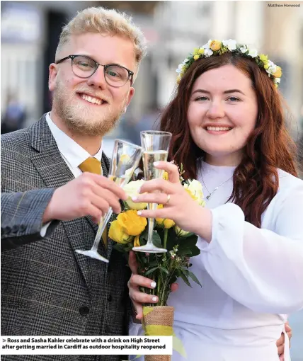  ?? Matthew Horwood ?? > Ross and Sasha Kahler celebrate with a drink on High Street after getting married in Cardiff as outdoor hospitalit­y reopened