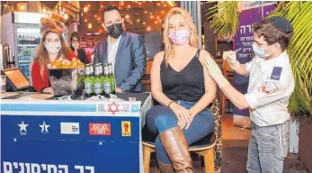  ?? FOTO: KFIR SIVAN/TEL AVIV-YAFO MUNICIPALI­TY/DPA ?? Clevere Idee: Eine junge Frau lässt sich vor einer Bar in Tel Aviv impfen. Die Stadtverwa­ltung spendiert dafür ein Getränk.