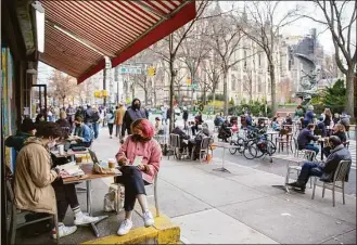  ?? Ted Shaffrey / Associated Press file photo ?? People eat at restaurant tables on a street block closed to vehicle traffic to allow social distancing and outdoor dining during the coronaviru­s pandemic in the borough of Manhattan in New York City on Dec. 13, 2020. As New York City forges ahead with its recovery, the pandemic is leaving lasting imprints, especially on city roadways: less room for cars and more space for people.