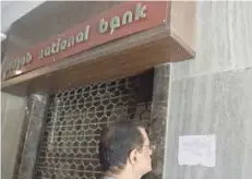  ?? — AFP ?? A man reads a notice by the CBI stating that the Brady House branch of Punjab National Bank has been sealed next to the entrance of the branch in Mumbai on Monday.