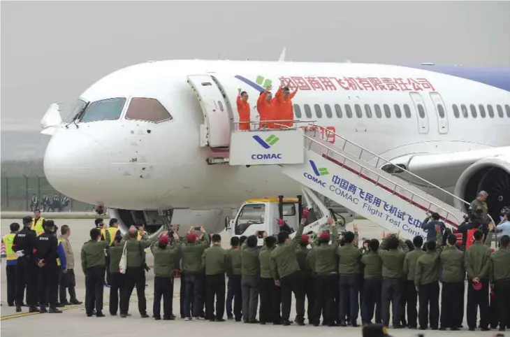  ??  ?? SHANGHAI: Crew members wave after completing the maiden flight of China’s home-grown C919 passenger jet at Pudong Internatio­nal Airport in Shanghai yesterday.—AFP