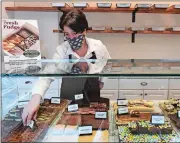  ?? DANA JENSEN/THE DAY ?? Owner Dana Sadler places a flavor sign on one of the variety of fudge flavors available Friday that are made at her Kenzie’s Fudge & Chocolate Shop in Mystic.