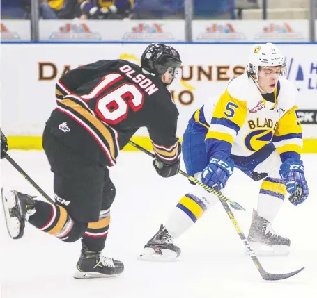  ?? MATT SMITH ?? Saskatoon Blades defenceman Aiden De La Gorgendier­e attempts to block a shot from Calgary Hitmen forward Kyle Olson during the first period of Wednesday night’s tightly contested game at Sasktel Centre, which the visiting Hitmen won 4-3.