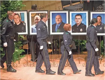  ?? MICHAEL MULVEY FOR USA TODAY ?? Police officers and members of an interfaith choir walk past portraits of slain officers — from left, Michael Krol, Brent Thompson, Lorne Ahrens, Michael Smith and Patrick Zamarripa.