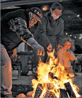  ??  ?? Volunteer Bill Palka helps Lauren Lorenz and her daughter, Charlotte, of Chicago, with their marshmallo­w roasting technique over an open bonfire.