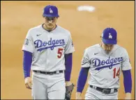  ?? Eric Gay The Associated Press ?? Los Angeles Dodgers shortstop Corey Seager (5) and teammate Enrique Hernandez walk off after Game 4 of the World Series on Saturday in Arlington, Texas.