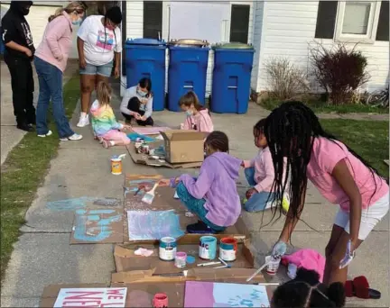  ?? PHOTOS COURTESY OF SWARM ?? Neighbors gathered to express their creativity and paint signs with positive messages for the Howard family.