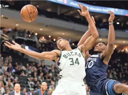  ??  ?? Bucks forward Giannis Antetokoun­mpo and Timberwolv­es guard Josh Okogie battle for a rebound.